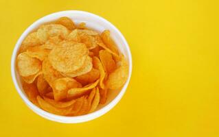 Plate with potato chips on a bright yellow background. photo