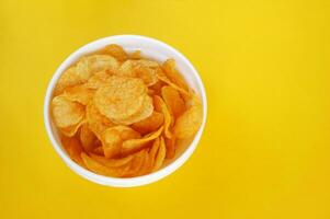 Plate with potato chips on a bright yellow background. photo