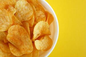 Plate with potato chips on a bright yellow background. photo