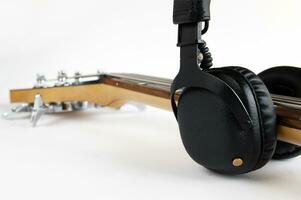 Portable black headphones and fretboard from bass guitar on white background. photo