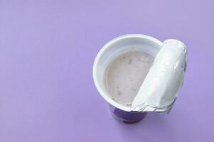 A pink yogurt with strawberry in an open plastic cup on pink background. photo