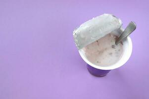A pink yogurt with strawberry in an open plastic cup on pink background. photo