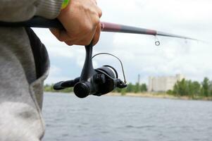 Wheel fishing rod closeup on a lake background. photo