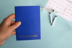 Blue International veterinary pet passport, syringe and ampoule with liquid on a light blue background. photo