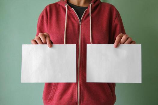 A young man holds two empty sheets of paper. photo