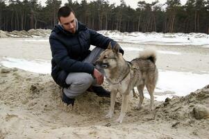 A young guy stroking his dog while walking. photo