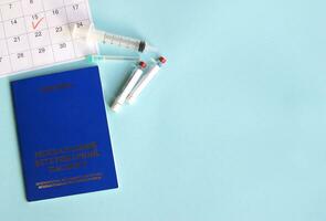 Blue Ukraine veterinary pet passport, syringe and ampoule with liquid on a light blue background photo