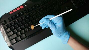 Cleaning the keyboard from dust with a brush in rubber gloves. photo