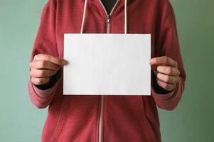 A young man holds an empty sheet of paper. photo