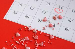 muchos pequeño rosado corazones y pelotas en el calendario marcado febrero 14 foto