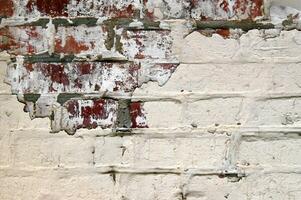 Old grunge red brick with peeled white plaster. photo