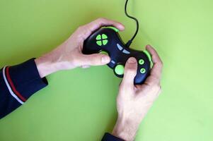 Male hands hold a gamepad in light green background. photo