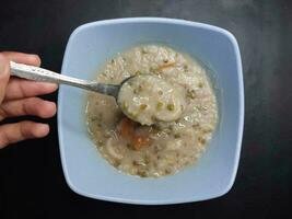 Bowl with tasty green bean porridge or Bubur kacang hijau on black background photo