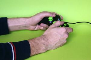 Male hands hold a gamepad in light green background. photo