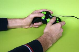Male hands hold a gamepad in light green background. photo