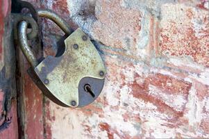 An old padlock on closed doors, a rusty lock on the gate. photo