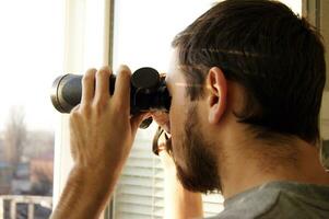 Young man standing looking with binoculars photo