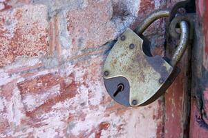 An old padlock on closed doors, a rusty lock on the gate. photo