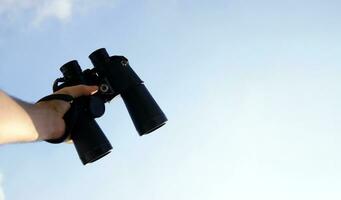 Hand with binoculars in the sky. photo