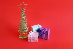 Golden metal Christmas tree with a star on top, red background. photo