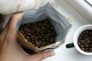 Hand holds an open package of coffee beans. photo