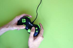 Male hands hold a gamepad in light green background. photo