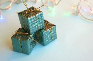 Navidad decoración para el Navidad árbol en el formar de pequeño brillante regalos en un azul antecedentes. foto