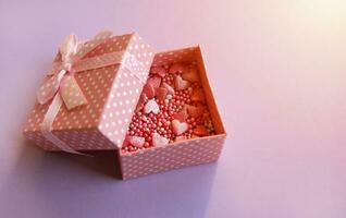 Gift open pink box with topping from hearts inside. photo