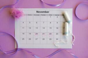 Menstrual tampons on menstruation period calendar with on lilac background. photo