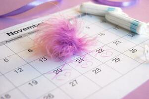 Menstrual tampons on menstruation period calendar with on lilac background. photo