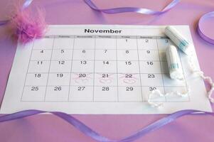 Menstrual tampons on menstruation period calendar with on lilac background. photo