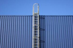 Blue background metal wall siding, cladding with stairs to the roof. photo