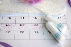 Menstrual tampons on menstruation period calendar with on lilac background. photo