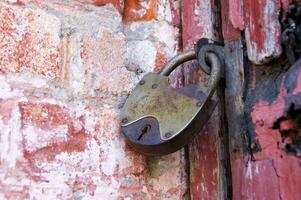 An old padlock on closed doors, a rusty lock on the gate. photo