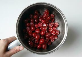 Frozen cherries in a metal ladle on a white background. photo