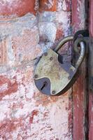 An old padlock on closed doors, a rusty lock on the gate. photo