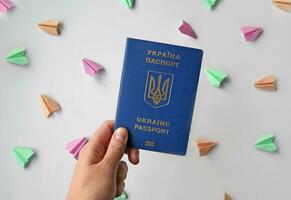 New Ukrainian biometric passport and colored paper planes on a white background. photo