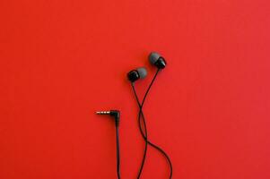 Headphones from the phone are on a red background. photo