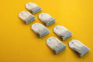 A lot of disposable tea bags on a yellow background. photo