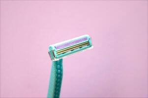 Closeup view with selective focus of disposable shaver isolated on abstract pink background. photo