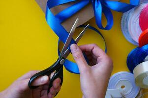 Gift box packaging on a yellow background. A lot of bright satin ribbons. photo