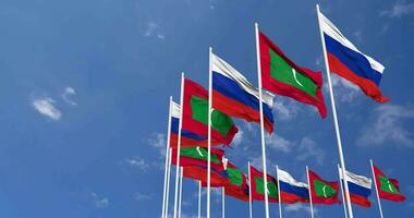Maldive e Russia bandiere agitando insieme nel il cielo, senza soluzione di continuità ciclo continuo nel vento, spazio su sinistra lato per design o informazione, 3d interpretazione video