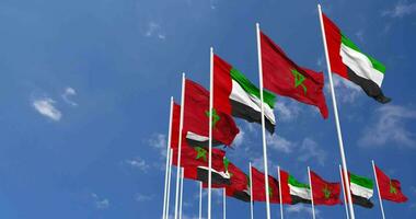 Marruecos y unido árabe emiratos, uae banderas ondulación juntos en el cielo, sin costura lazo en viento, espacio en izquierda lado para diseño o información, 3d representación video