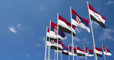 Serbia e yemen bandiere agitando insieme nel il cielo, senza soluzione di continuità ciclo continuo nel vento, spazio su sinistra lato per design o informazione, 3d interpretazione video