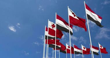 Tonga und Jemen Flaggen winken zusammen im das Himmel, nahtlos Schleife im Wind, Raum auf links Seite zum Design oder Information, 3d Rendern video