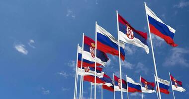 Serbia e Russia bandiere agitando insieme nel il cielo, senza soluzione di continuità ciclo continuo nel vento, spazio su sinistra lato per design o informazione, 3d interpretazione video