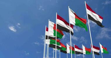 Madagascar y Yemen banderas ondulación juntos en el cielo, sin costura lazo en viento, espacio en izquierda lado para diseño o información, 3d representación video