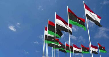 Libia y Yemen banderas ondulación juntos en el cielo, sin costura lazo en viento, espacio en izquierda lado para diseño o información, 3d representación video