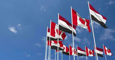 Canadá y Yemen banderas ondulación juntos en el cielo, sin costura lazo en viento, espacio en izquierda lado para diseño o información, 3d representación video