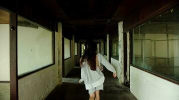 Girl walking down a scary hallway in an abandoned building, rear view video